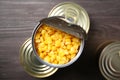 Open tin can of sweet corn and conserves on wooden table