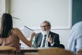 Elderly gray-headed man, professor, teacher and students at lecture, lesson at classroom, indoors. Concept of