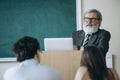 Elderly gray-headed man, professor, teacher and students at lecture, lesson at classroom, indoors. Concept of