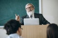 Elderly gray-headed man, professor, teacher and students at lecture, lesson at classroom, indoors. Concept of