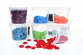 Red plastic snap fastener buttons spilling out with containers with colorful snaps in background