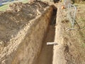 Open trench with small diameter water pipe and heap of ground