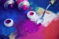 Open tubes of purple and pink colors paint and a palette knife are on the palette