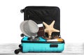 Open turquoise suitcase with  beach objects on wooden table, white background Royalty Free Stock Photo