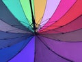 An open umbrella is bright, multi-colored, close-up. Background texture: umbrella mechanism. Large rain umbrella, all colors of