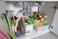 Open under sink cabinet with different cleaning supplies in kitchen