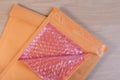 Open used yellow blank envelope with transparent bubble wrap or packaging shockproof on wooden table.