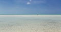 open view of Cuban Cayo Coco island wild beach with turquoise, tranquil ocean and person going far toward horizon line