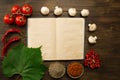 Open vintage book with berries, tomatoes, Chile peppers, spices and grape leaf on wooden background. Healthy vegetarian food. Royalty Free Stock Photo