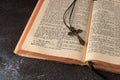 Open vintage holy bible with german text in old print and metal catholic cross with crucifix and ornament on dark grunge