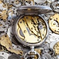 Open vintage pocket watch on pile of spare parts