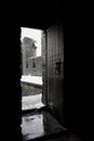 Open vintage wooden door in medieval castle. Narrow wooden entrance to castle yard with brick walls. Winter view open door.