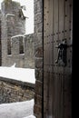 Open vointage wooden door in medieval castle. Narrow wooden entrance to castle yard with brick walls. Winter view open door.