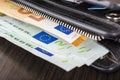 Open wallet with euro cash 10 20 50 100 on a wooden background. Men`s wallet with cash euro. Royalty Free Stock Photo