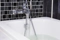 Open water from faucet to bathtub in bathroom Royalty Free Stock Photo