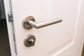 Open the white door. Modern chrome handle in your hotel room or home. Entrance to an apartment, office, or bedroom. Door detail. Royalty Free Stock Photo