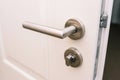 Open the white door. Modern chrome handle in your hotel room or home. Entrance to an apartment, office, or bedroom. Door detail. Royalty Free Stock Photo