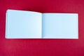 Open white horizontal notebook mock up on red paper background. Empty sketchbook for artists. Royalty Free Stock Photo