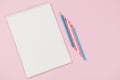 Open blank white notebook and light blue, pink, white colored pencils on pastel pink background. Top view, copy space Royalty Free Stock Photo