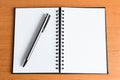 Open white paper notebook with business silver stylish pen on the left side, on a warm natural wooden desk background, top view wi Royalty Free Stock Photo