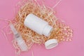 An open white plastic bottle lies on decorative hay, yellow capsules spilled out of the bottle. White bottle of nasal spray. Royalty Free Stock Photo