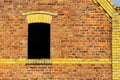 Open window with dark black interior on a grungy red brick wall with yellow details of a vintage old barn or warehouse Royalty Free Stock Photo