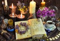 Open witch book with spells, black candles and cup of coffee.