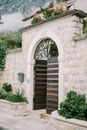 Open wooden arched door in a stone fence
