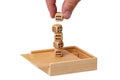 On an open wooden box a hand stacks playing cubes to form a tower. Isolated on white. Macro. Business concept. Mock up