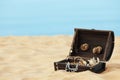 Open wooden chest with treasures on sandy beach, space for text Royalty Free Stock Photo