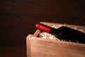 Open wooden crate with bottle of wine, space for