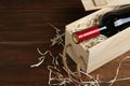 Open wooden crate with bottle of wine on table, space for