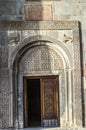 Wooden door, covered with a carved ethnic ornament, and a stone oval plane with carved fruit patterns above the doorway church of Royalty Free Stock Photo