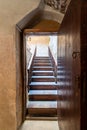 Open wooden door revealing wooden old staircase going up with with reflections of the stairs on the door Royalty Free Stock Photo