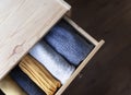 Open wooden dresser drawer with warm knitted woolen clothes. Home vertical storage. Wardrobe organizing