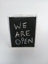 We are open written on a chalkboard on a white background