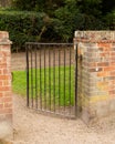 Open wrought iron gate between two brick pillars