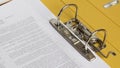 Open yellow binder close up, stack of white papers and bright metal rings