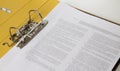 Open yellow binder close up, stack of white papers and bright metal rings