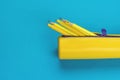 An open yellow pencil case with pens and pencils on a blue background. Flat lay Royalty Free Stock Photo