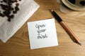 Open your mind text handwritten on sticky note with coffee and pen Royalty Free Stock Photo