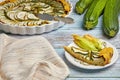 Open zucchini tart with herbs and cheese curd filling in a baking dish and sliced