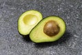 Opened avocado showing seed on textured stone background