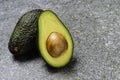 Opened avocado showing seed on textured stone background
