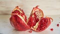 Opened big red pomegranate with seeds on the white concrete bckground. Sliced fresh pomegranate on the light wooden background