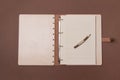 Opened big wooden notebook with pen ready to write on brown colored paper background. Top view Royalty Free Stock Photo