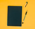 Opened black colored ball point pen placed beside a black colored paper diary on an orange background Royalty Free Stock Photo