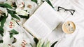 Opened book, coffee cup, glasses and fresh flowers on the white bed. Flat lay, top view Royalty Free Stock Photo