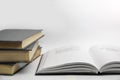 The opened book lies next to a stack of closed books on a gray background.