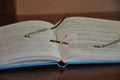 Opened book and reading glasses lying on brown table. Glasses on an open book. Shallow depth of field.